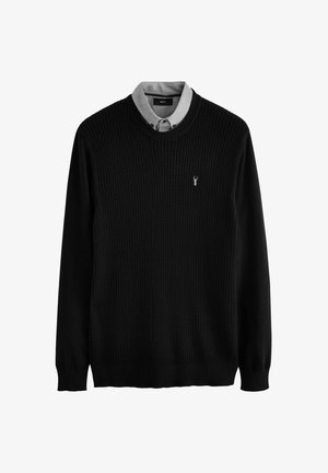 Black knitted sweater with a textured design, featuring a gray collared shirt underneath. Small logo accent on the chest.