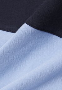 Gros plan sur un tissu lisse montrant des sections pliées en bleu marine et bleu clair avec une texture tricotée visible.