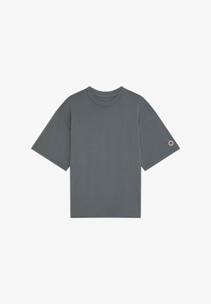 T-shirt gris foncé à manches courtes et col rond avec un petit logo circulaire sur la manche gauche, présenté sur un fond blanc.