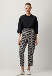 Black oversized t-shirt, patterned high-waisted pants in cream and navy, and white sneakers, with a cropped fit and straight legs.