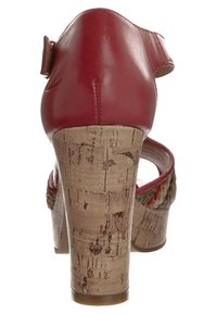 Czerwone skórzane sandały na wysokim obcasie z korkowym koturnem. Posiadają tylny pasek oraz teksturowaną wkładkę z kwiatowym akcentem wokół kostki.