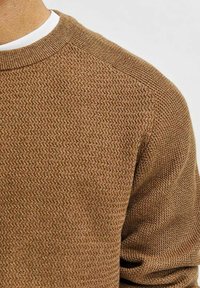 Ruskea tekstuuri neulepaita, jossa pyöreä kaula-aukko, näkyvä neulekuvio ja resorireunat hihansuissa sekä helmassa.