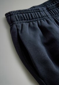 Dark blue jogger pants made of soft material with an elastic waistband and side pockets, featuring a smooth texture and simple design.