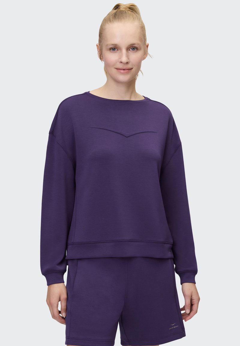 Purple sweatshirt with a round neckline and a subtle V-shaped stitch detail on the front. Soft texture, paired with matching shorts.