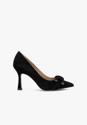 Chaussure à talon haut en suede noir avec un bout pointu et un détail de nœud décoratif à l'avant. Elle présente un talon stiletto fin et un doublage en cuir.