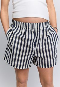Pantaloncini a righe con strisce verticali blu navy e crema, vita elasticizzata, tasche laterali e vestibilità comoda.