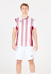 Rød og hvid stribet atletisk skjorte med korte ærmer, parret med hvide shorts med et logo. Glat tekstur, sporty design.