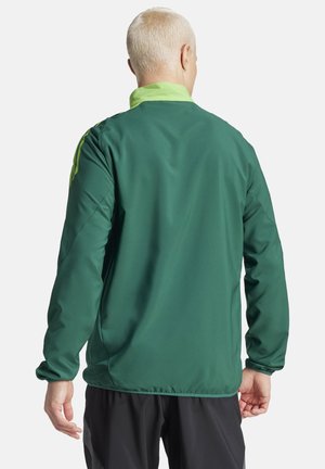 Grüne Windjacke mit hohem Kragen, kontrastierenden hellgrünen Akzenten und langen Ärmeln; glatte Textur und figurbetontes Design.