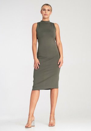 Oliwkowa, bezrękawnikowa sukienka midi w fasonie bodycon z wysokim dekoltem i gładką fakturą, w zestawieniu z przezroczystymi sandałami na słupku.