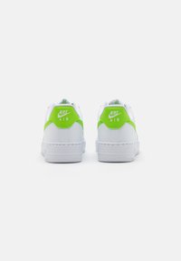 Par vit Nike Air-sneakers sedd från baksidan, med ljusgröna detaljer och Nike-logotypen på hälfliken.