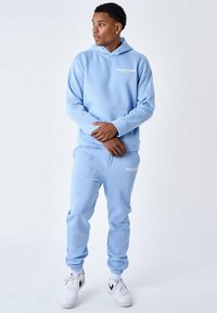 Lichtblauwe hoodie en sweatpants set gemaakt van zachte stof, met witte tekstlogo's, elastische boorden en een kangoeroezak.