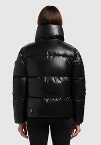 Veste matelassée noire avec une finition brillante, dotée d'un col montant et de sections matelassées horizontales. Petite écusson logo sur le côté gauche.