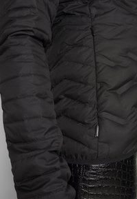 Giacca a vento nera con modello trapuntato, dotata di colletto alto, chiusura con zip e discreta marchiatura all'orlo. Finitura liscia e opaca.