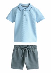 Tricou polo de culoare albastru deschis, cu un model texturat și guler contrastant, combinat cu pantaloni scurți gri, cu un braț elastic și buzunare laterale.
