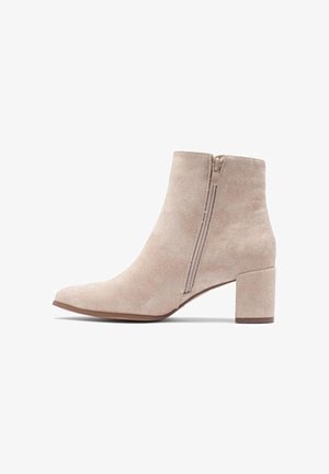 Hellbeige Wildleder-Stiefelette mit seitlichem Reißverschluss, rundem Zehenbereich und Blockabsatz auf weißem Hintergrund.