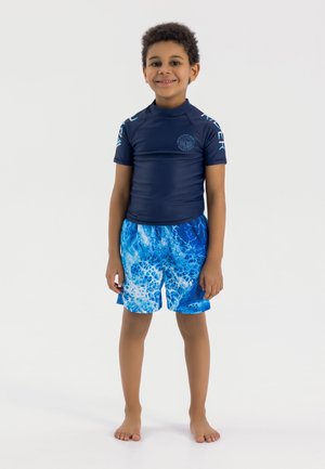 T-shirt de surf bleu à manches courtes, avec un design contrasté sur les épaules, assorti à un short de bain bleu arborant un motif marbré aquatique.