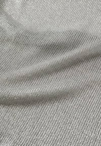 Gros plan sur un tissu tricoté métallique argenté avec des fils fins et brillants et des plis doux créant une surface texturée.