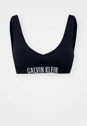 Mustmustel mustriba laiade õlgadega ja V-kaelusega. Alumisel äärel on valge bränditud elastne riba. Sujuv, veniv kangas.