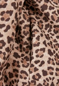 Fabric with brown and black leopard print pattern, showing folds and texture.