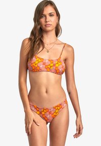 Bikini-tyyppinen asu, jossa on geometrisia kuvioita persikka, oranssi ja violetti väri. Valmistettu sileästä kankaasta, ohuilla olkaimilla ja matalalla vyötäröllä.