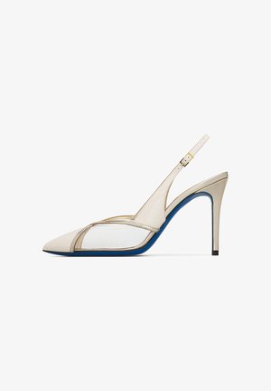 Décolleté slingback crema con punta a mandorla, pannelli laterali trasparenti e dettaglio suola blu su sfondo bianco.