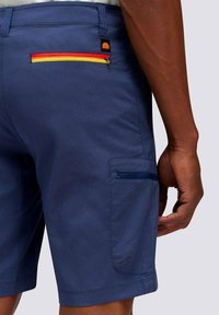 Pantaloni corti blu navy con finitura testurizzata, dotati di una tasca posteriore con zip multicolore e di una tasca laterale.