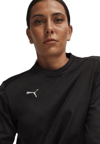 Top atletico nero con scollatura a girocollo, texture liscia e un grande logo Puma bianco sulla parte sinistra del petto.