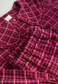 Sarkana un melna šaha raksta flaneļa pidžamu krekls un bikses ar īsām piedurknēm, pogu aizdari un elastīgu jostasvietu. Mīksta tekstūra un ikdienišķs dizains.