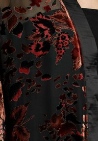 Material de catifea neagră, cu modele florale roșii și bordeaux. Un overlay transparent adaugă textură, cu accente de satin neted pe margini.