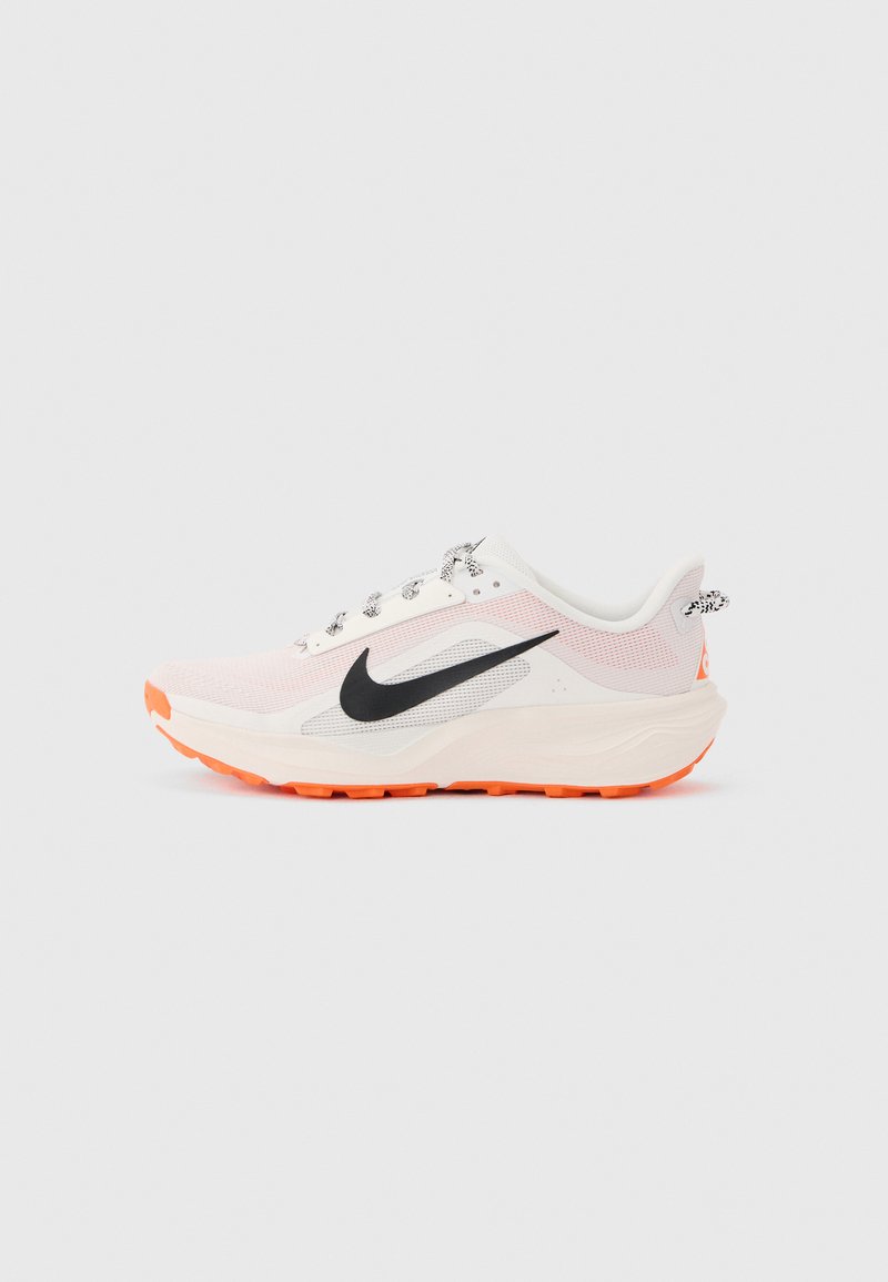 Λευκό και ανοιχτό ροζ παπούτσι τρεξίματος Nike με μαύρο λογότυπο swoosh και πορτοκαλί σόλα, απεικονιζόμενο από το πλάι σε ουδέτερο φόντο.