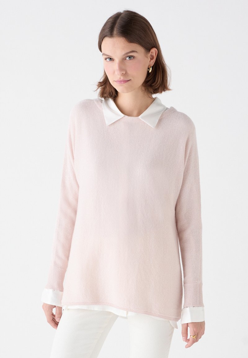 Maglione a maglia rosa chiaro con colletto bianco, maniche lunghe e polsini a coste. Il tessuto testurizzato appare morbido e leggermente lucido.