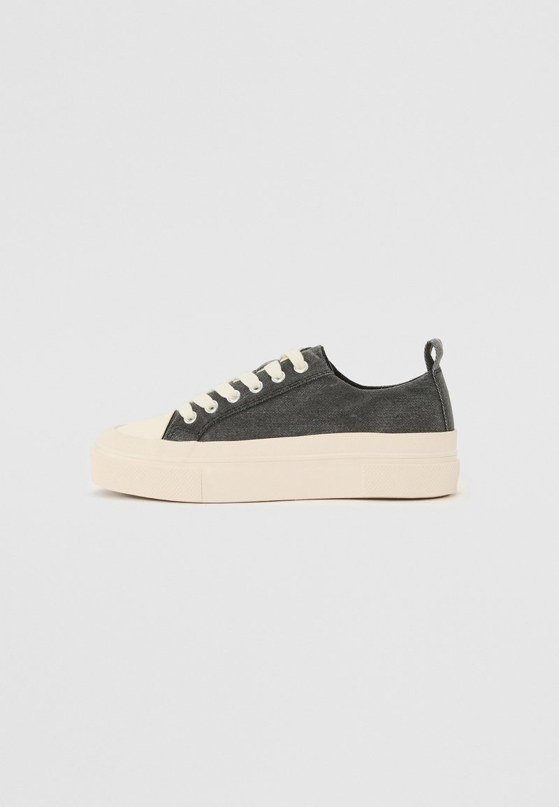 Canvas-Sneaker in Dunkelgrau mit beigen Gummisohlen, runder Zehenpartie und weißen Ösen. Mit einer Stoffschlaufe an der Ferse für ein einfaches Anziehen.