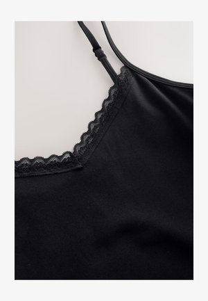 Camisole noire avec bretelles réglables et dentelle le long du décolleté en V sur un fond clair uni.