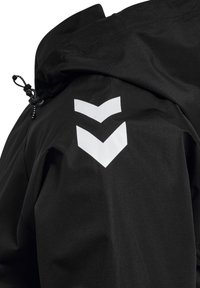 Détail d'épaule de veste noire avec deux bandes chevrons blanches vers le bas et un cordon réglable près du col.