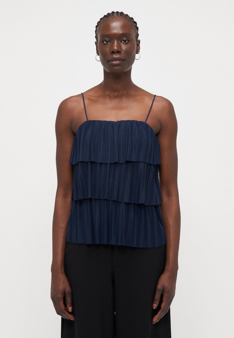 Navy blue pleated top with three layered ruffles, thin spaghetti straps, and a straight hem. Fabric has a smooth texture.