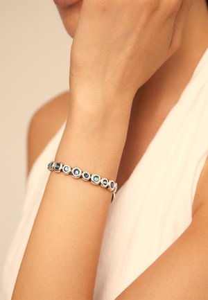 Bracelet en argent avec des pierres circulaires bleues et turquoise, alternant dans le design, présentant une surface lisse et polie et des sertissages ronds.