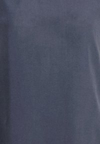 Tessuto blu scuro con una superficie liscia e una leggera lucentezza, caratterizzato da un design semplice senza motivi o accenti aggiuntivi.