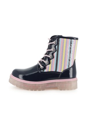 Botte de combat noire brillante avec des lacets roses, une semelle translucide et un panneau en tissu rayé multicolore avec des sequins sur le côté.
