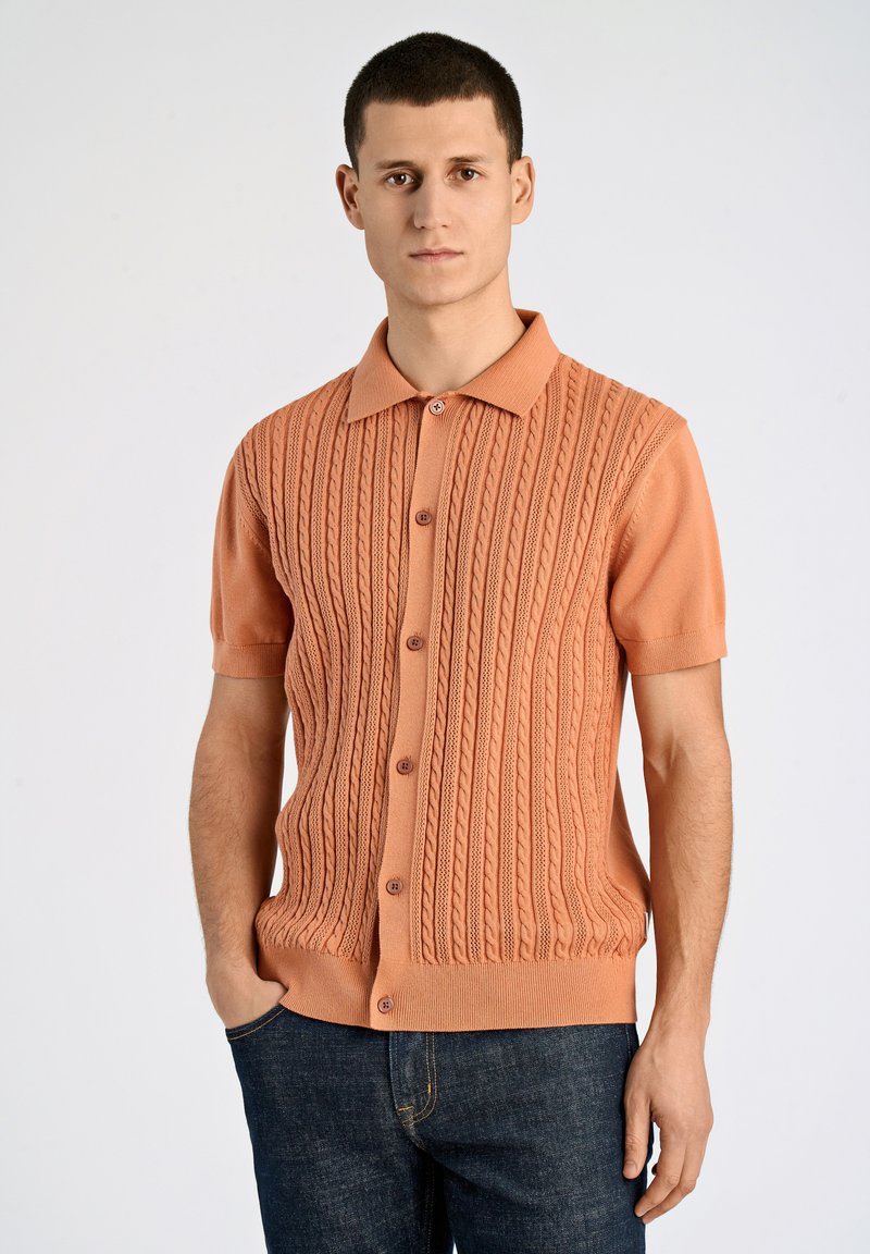 Kurzärmliges, geripptes Strickshirt in Koralle mit Kragen und durchgehender Knopfleiste. Strukturierter Kabelstrickdesign über das gesamte Shirt.