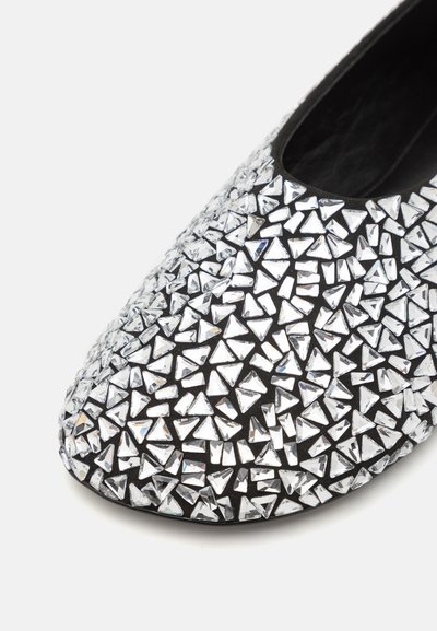 Chaussure noire recouverte de petites paillettes triangulaires réfléchissantes. Bout arrondi avec un intérieur noir doux et une surface texturée. Semelle plate.
