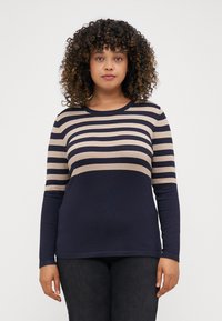 T-shirt à manches longues avec des rayures horizontales bleu marine et beige. Col rond, design ajusté, fabriqué en tissu doux. Assorti avec un jean foncé.