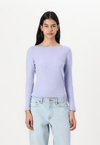 Light purple long-sleeve top with a boat neckline, made of soft material, paired with light blue high-waisted jeans, featuring front pockets.