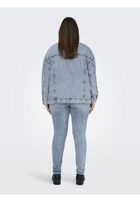 Světlomodrá džínová bunda s uvolněným střihem, spárovaná s odpovídajícími úzce střiženými džíny. Obsahuje detaily šití a klasickou siluetu.
