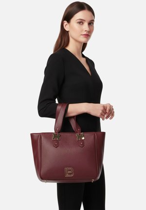 Borsa tote in pelle bordeaux con finitura testurizzata, dettagli in metallo dorato e logo pronunciato. Dotata di doppi manici e design strutturato.