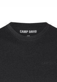 T-shirt di cotone nera con scollatura rotonda. Presenta il logo in rilievo "CAMP DAVID" nello stesso colore sul petto e sul retro del collo.