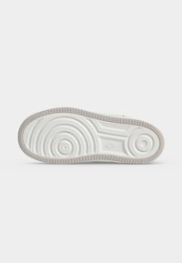 Σόλα ενός λευκού αθλητικού παπουτσιού Nike με κυκλικά σχέδια πέλματος και το λογότυπο της Nike ανάγλυφο στη μέση.