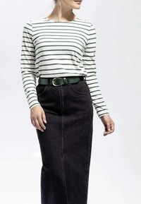 Langærmet, stribed skjorte i hvid og grøn parret med et sort denimskørt, accentueret af et grønt bælt med en sølvspænde.