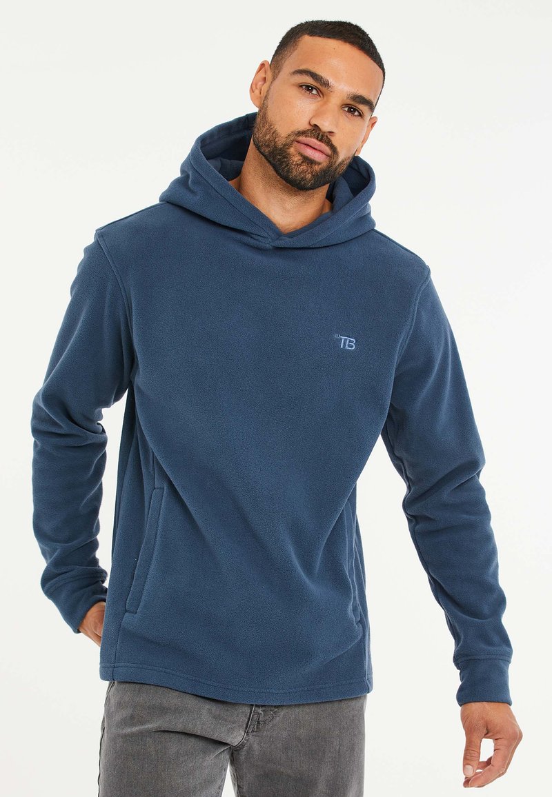 Marineblauwe fleece hoodie met lange mouwen, een vozakje en een logo op de borst. Zachte textuur en een ontspannen pasvorm.