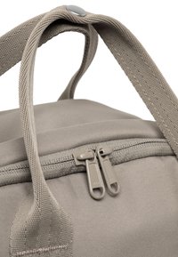 Borsa in tessuto grigio con doppie cerniere e manici intrecciati. Presenta una superficie liscia e un bottone decorativo sulla maniglia.