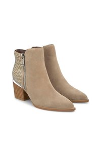 Bottes de cheville en suède beige avec un bout pointu, un dos texturé ornés de clous métalliques, et une fermeture éclair sur le côté. Design à talon carré.